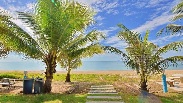 Una playa con palmeras, cielo despejado y mar tranquilo.