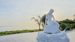 Una estatua de una mujer sobre una roca junto al mar.