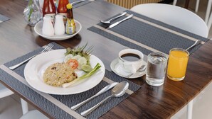 Una mesa de comedor con un plato de comida, condimentos, cubiertos, una taza de café, un vaso de agua y un vaso de zumo de naranja.