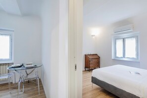 Une chambre à coucher avec un lit, une commode, une table avec des chaises et une fenêtre.