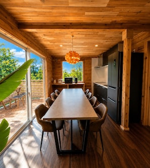 Une cuisine moderne avec un plafond en bois, une table à manger avec des chaises et une vue sur l’extérieur.