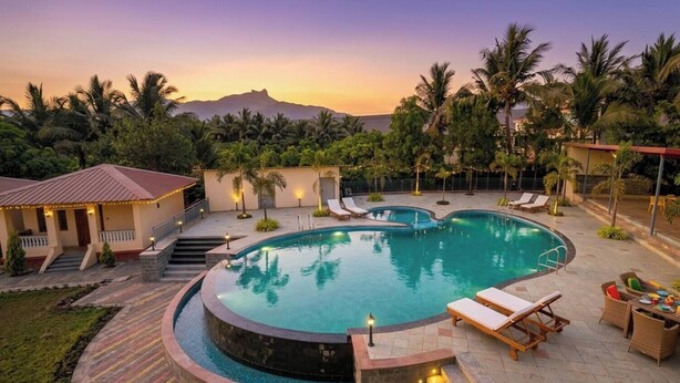 Una piscina circular con sillones de descanso, una escalera y un edificio con techo rojo.