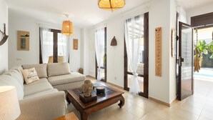 Un salon spacieux avec un canapé, une table basse en bois et un luminaire suspendu.