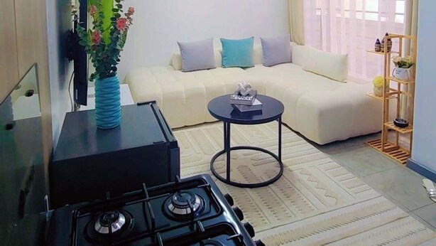 Una sala de estar con sofá, mesa de centro, televisor y un área de cocina con estufa.