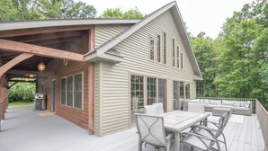 Une maison dotée d’un porche abrité, d’un coin repas avec une table et des chaises, et d’une grande fenêtre.