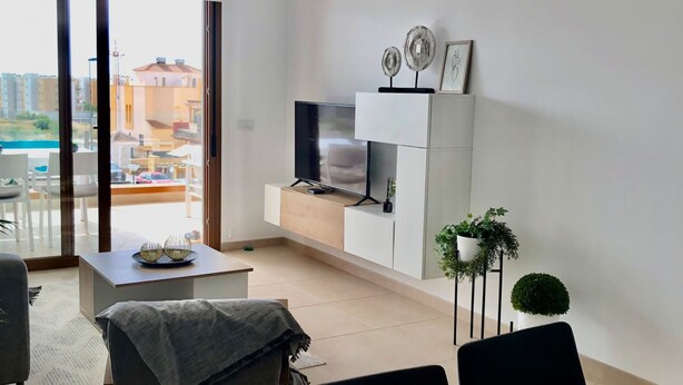 Un salon moderne comprenant un canapé, une table basse, un t éléviseur et un coin repas avec une table et des chaises.