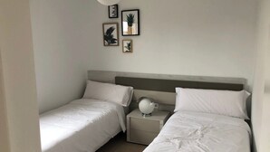 Une chambre avec deux lits simples, une table de chevet avec une lampe et des œuvres d’art murales.