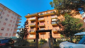 A multi-story residential building with balconies, a gated entrance, and parked cars. - Familiar base for a comfortable stay in Rosolina (Rosolina Mare)