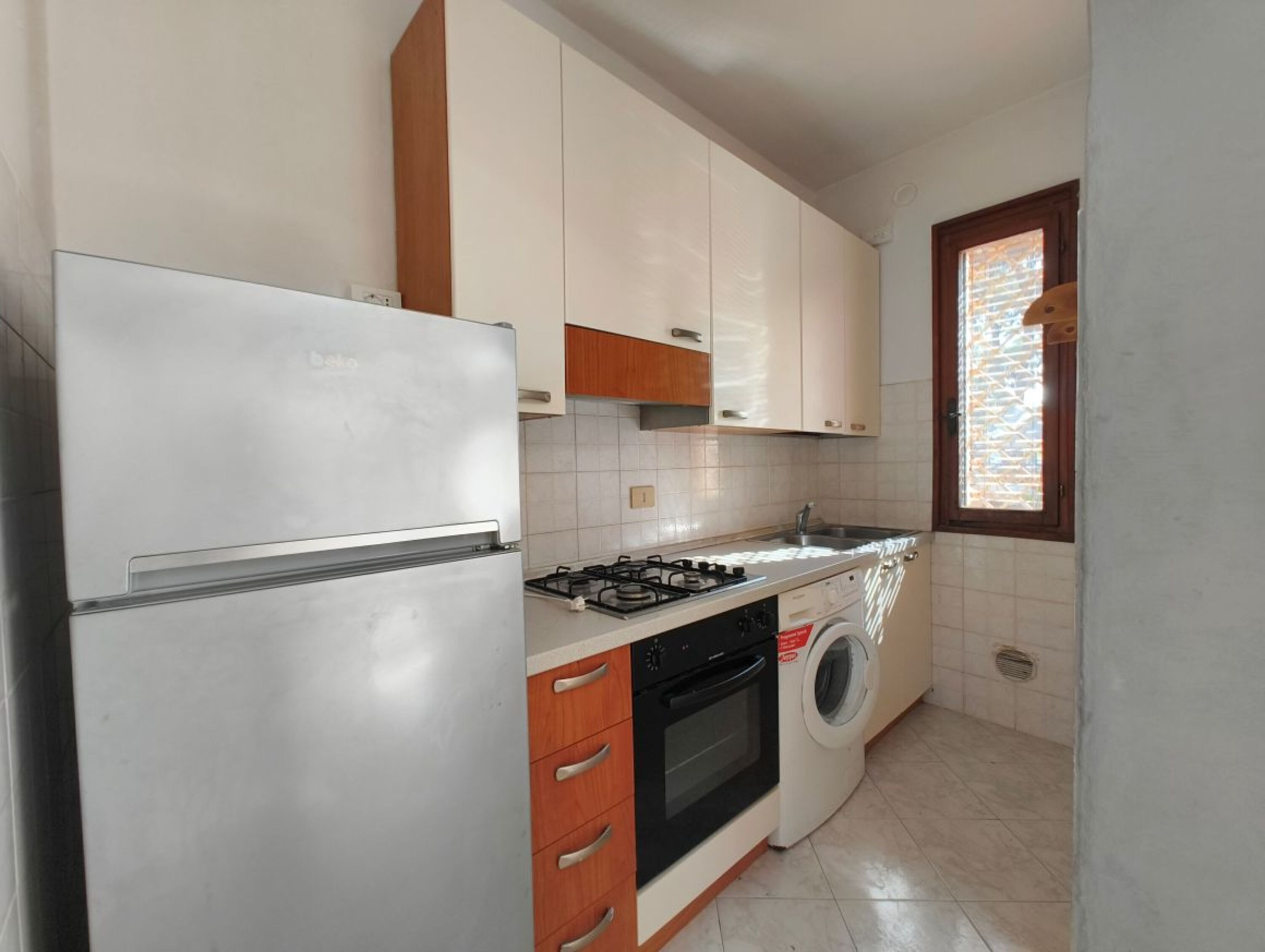 Eine Küche mit Kühlschrank, Herd, Backofen und Waschmaschine.