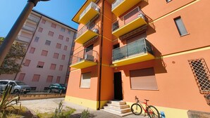A multi-story residential building with balconies, a bicycle, and a street lamp. - Familiar base for a comfortable stay in Rosolina (Rosolina Mare)