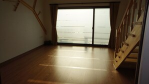Una habitación con piso de madera, puerta corredera de vidrio y escalera de madera.