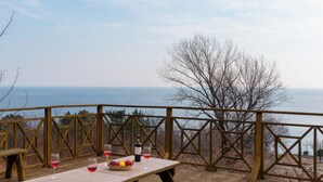 Una terraza de madera con una mesa preparada para comer, con vista a un cuerpo de agua.