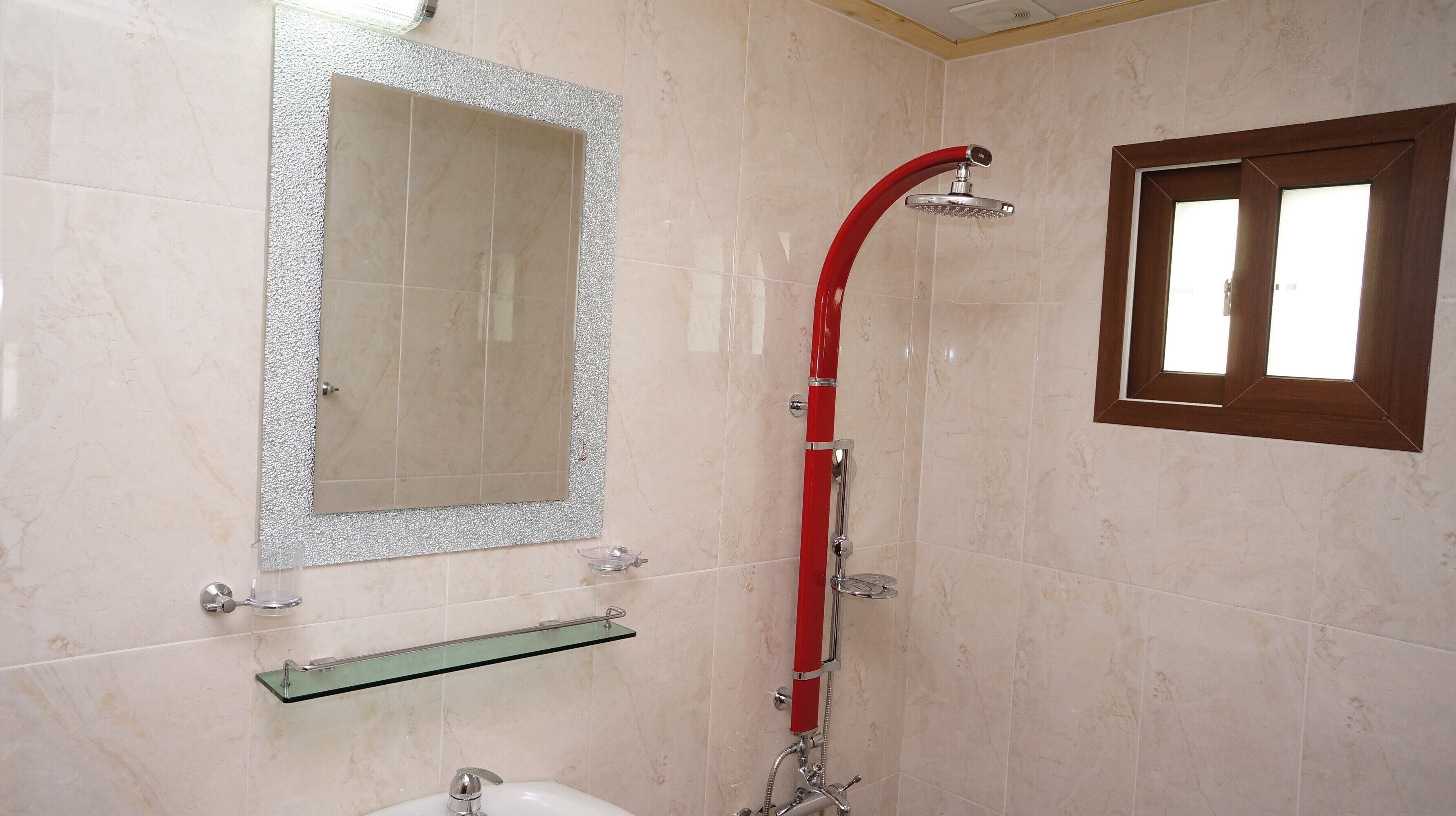 A bathroom with a shower, a mirror, and a window.