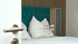 A bed with white bedding and a teal upholstered headboard. - Mersa Hotel (Backnang)