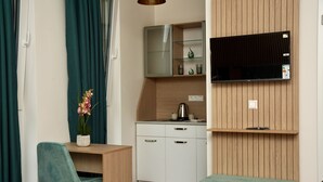 A kitchenette with a microwave, a small cabinet, and a countertop. There is a chair and a bench in the room. - Mersa Hotel (Backnang)