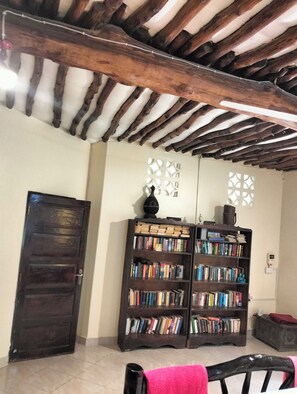 A room with a wooden ceiling, a dark wooden door, and two bookshelves filled with books.