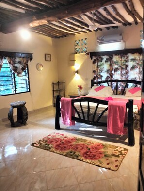 A bedroom with a bed, a nightstand, a wall clock, a window with bars, and a ceiling fan.