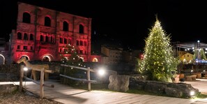 Ein historisches Gebäude mit Bogenfenstern, einem Weihnachtsbaum und einer hölzernen Bank.