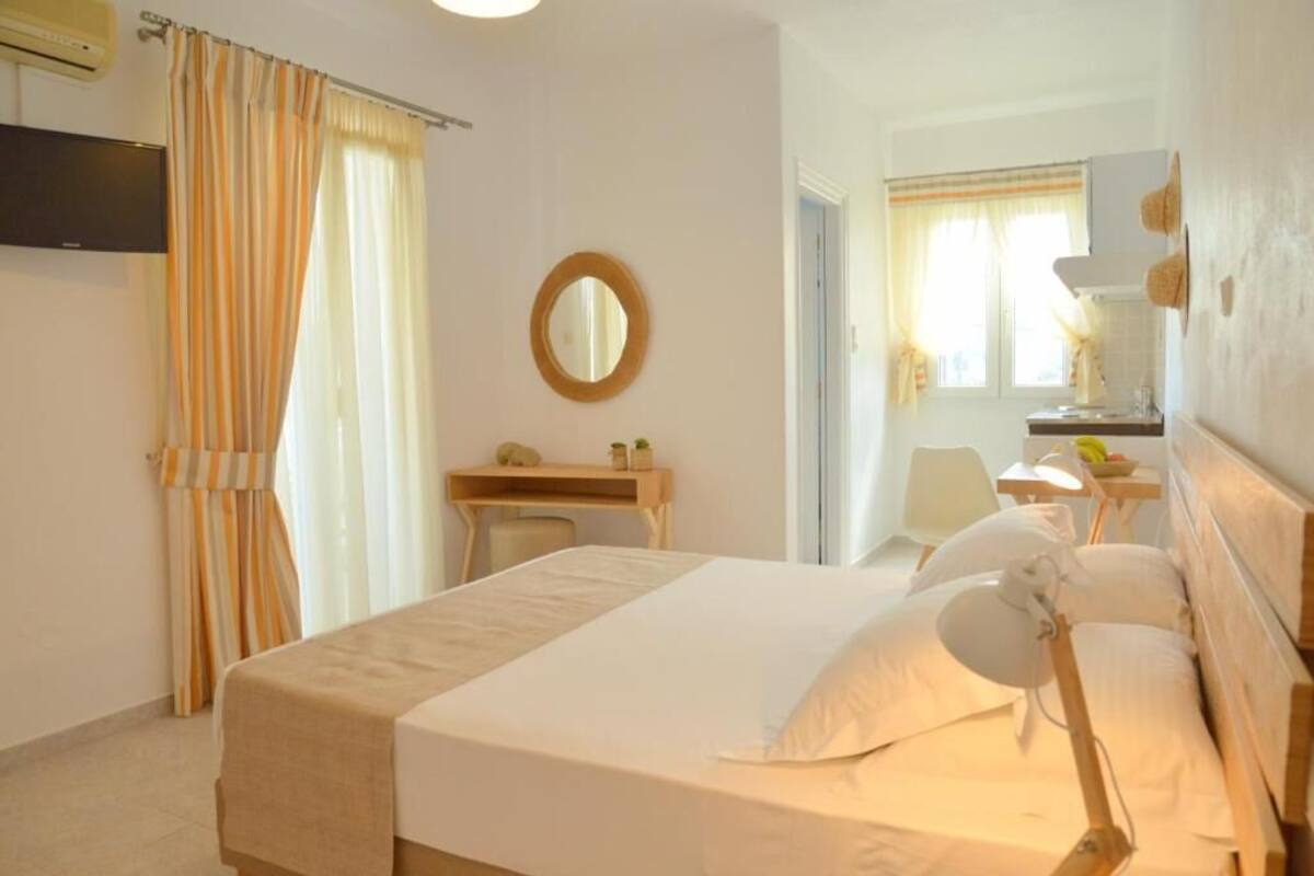 A hotel room with a bed, a desk, a chair, a mirror, and a window with curtains.