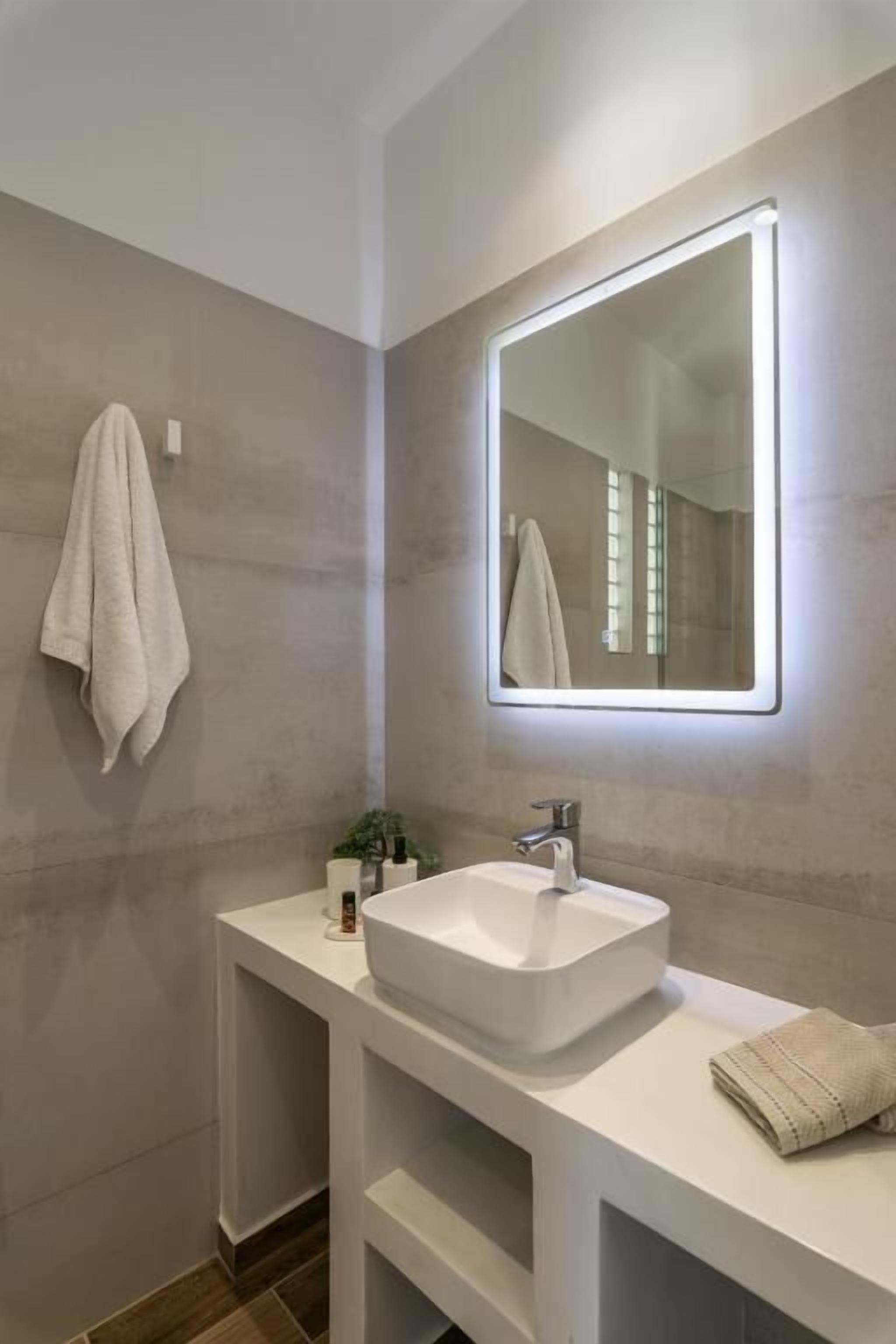 A modern bathroom with a large mirror, white vanity, and a towel rack.