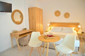 Ein Schlafzimmer mit einem Bett, Nachttischen, einem Schreibtisch, zwei Stühlen, einem Fernseher und einem wandmontierten Spiegel.