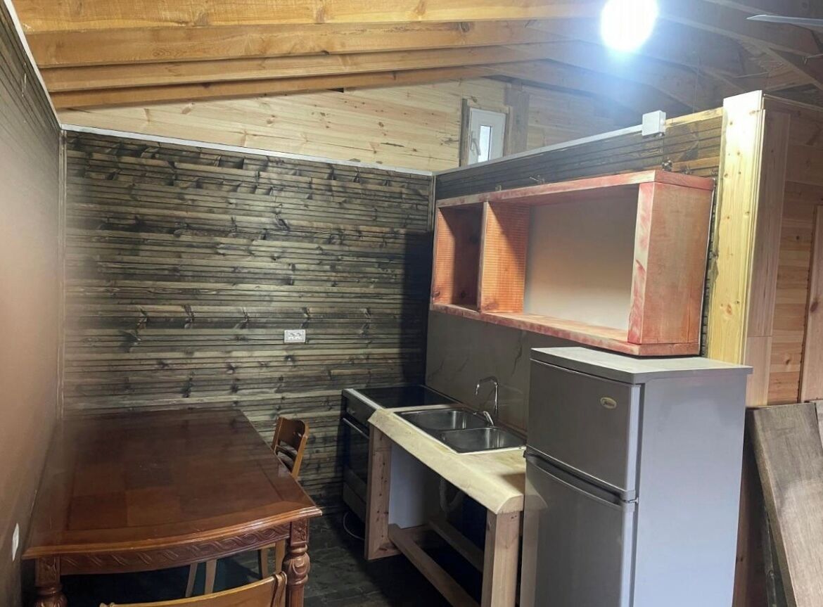 Een kleine keuken met een houten tafel, een gootsteen en een koelkast.