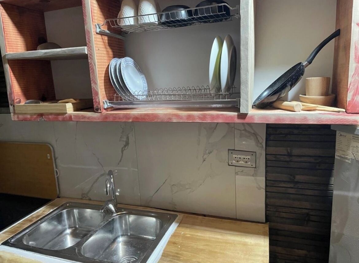 A kitchen with a sink, dish rack, and utensils.
