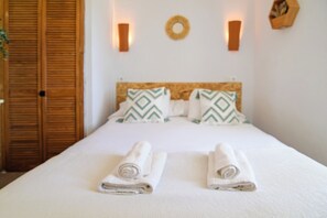 A neatly made bed with pillows, a wooden headboard, and two wall-mounted lights. - La Calma deVilo (Vilo)