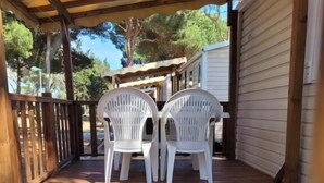 Een houten terras met twee witte plastic stoelen en een witte tafel.