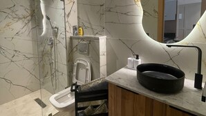 Um banheiro moderno com painel de mármore, pia preta e espelho oval singular.