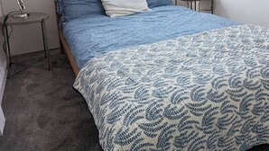A bedroom with a skylight, a bed with blue bedding, two bedside tables with lamps, and a view of the outside. - Cosy loft on the beach (Tramore)