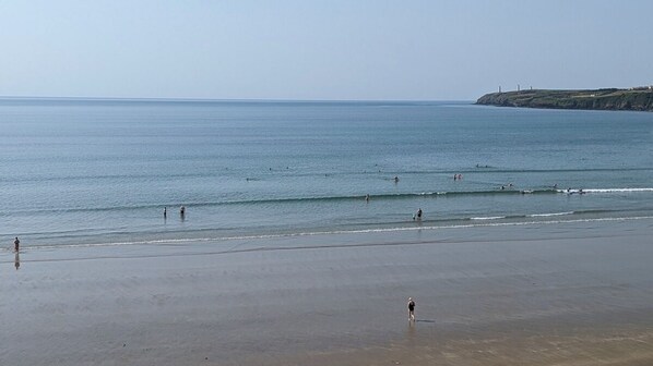 A beach with people swimming and walking along the shore.