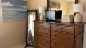 Un dormitorio con un aparador de madera, un televisor y un espejo.