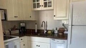 Una cocina con armarios blancos, lavavajillas y refrigerador.