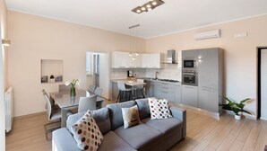 A modern kitchen with a dining area, a gray sofa with patterned cushions, and a potted plant. - Apartment 'Diegopas' with Sea View, Wi-Fi and Air Conditioning (Sant'Antonio Abate)
