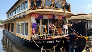 Ein Hausboot mit einer überdachten oberen Deckfläche, Fenstern und einem Balkon.