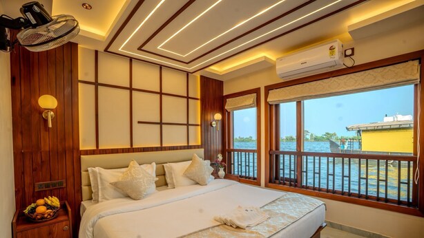 Ein Hotelzimmer mit Bett, Nachttisch, Lampe, Klimaanlage und Blick auf das Wasser.