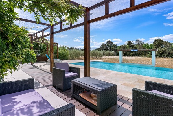 A poolside area with wicker furniture, a covered seating area, and a view of a swimming pool. - “Domaine des Lucques” Guest Room with Private Pool, Wi-Fi, and Air Conditioning (Mirepeisset)