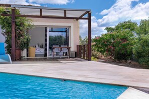 A poolside area with a covered seating area, a clear view of the pool, and a wooden pergola structure. - “Domaine des Lucques” Guest Room with Private Pool, Wi-Fi, and Air Conditioning (Mirepeisset)