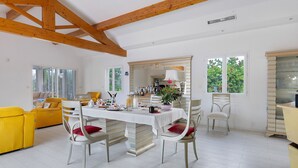 Un coin repas avec une table blanche, des chaises et un canapé jaune.