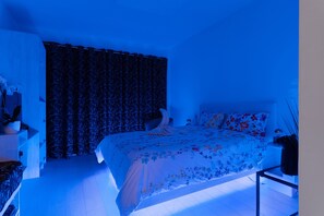 A bedroom with a bed, curtains, a nightstand, and a lamp. - “Domaine des Lucques” Guest Room with Private Pool, Wi-Fi, and Air Conditioning (Mirepeisset)