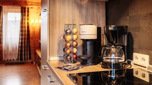 Ett kök med en kaffebryggare, en Krups-kaffekanna och en kaffekanna i glas på bänkskivan.