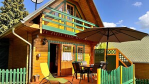 Eine Holzhütte mit Balkon, Essbereich und überdachter Terrasse.
