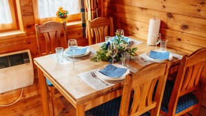 Ein Holzespeisetisch ist mit blauen Servietten, Tellern und Gläsern gedeckt und von Holzstühlen umgeben.