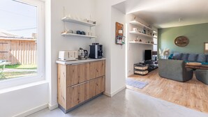 A modern kitchen with built-in appliances, wooden cabinets, and white shelves. - Charming Oléron Holiday Home Near Beach with Terrace, Private Garden & Wi-Fi (Saint-Pierre-d'Oléron)