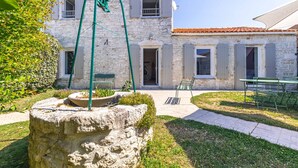 A stone building with a garden, outdoor seating, and a water feature. - Charming Oléron Holiday Home Near Beach with Terrace, Private Garden & Wi-Fi (Saint-Pierre-d'Oléron)