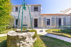 Ein Steinhaus mit Garten, Außenbestuhlung und einem Wasserspiel.