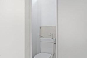 A small, white bathroom with a toilet and a sink. - Charming 2BR Retreat by République (Paris)