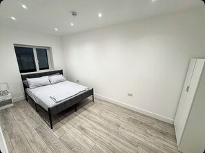 Une chambre à coucher avec un lit, une table de chevet, une fenêtre et une porte.