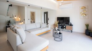 Uma sala de estar moderna com sofá seccional, televisão e decoração minimalista.